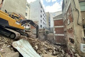 İzmir'in Konak il&ccedil;esinde,&nbsp;şantiye sahasında &ccedil;alışılan iş makinesinin u&ccedil; kısmı,&nbsp;bitişik apartmandaki