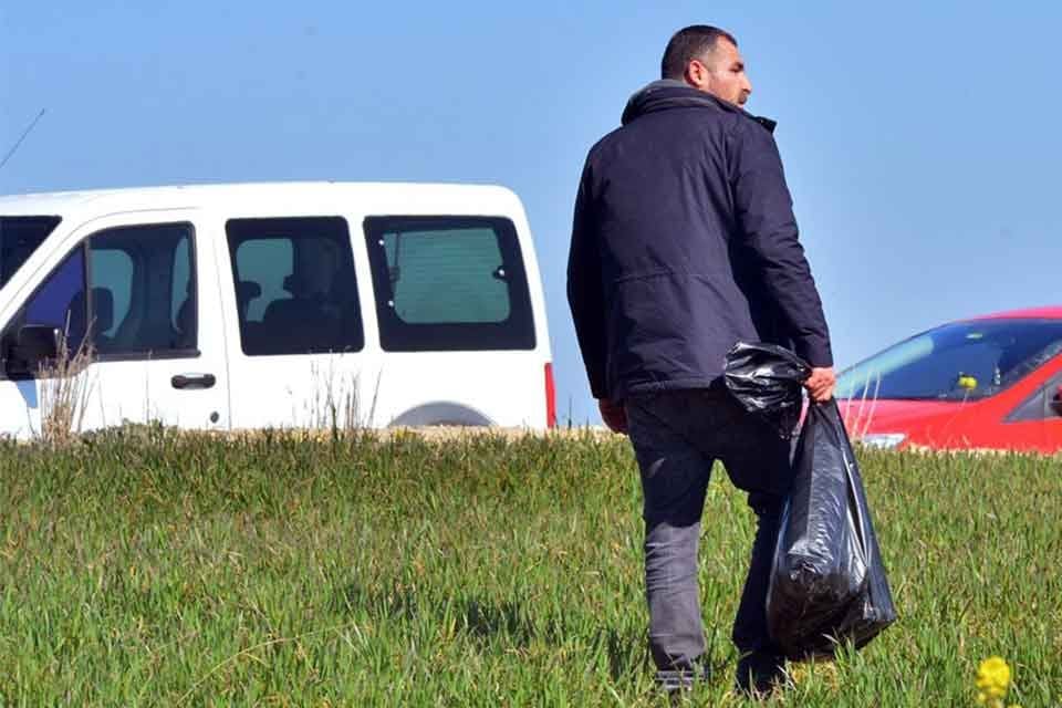 Adana'da yıkılan binaların enkazının toplandığı boş arazisinde depremzedeler, molozlar arasında
