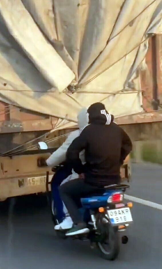 Muğla’da, kara yolunda, kasksız motosiklet sürücüsünün kamyona tutunup ilerlediği tehlikeli