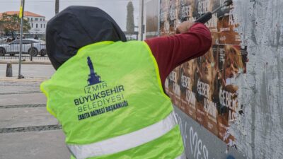 Elektrik direkleri, duvarlar ve üst geçitler korsan afişlerden tek tek